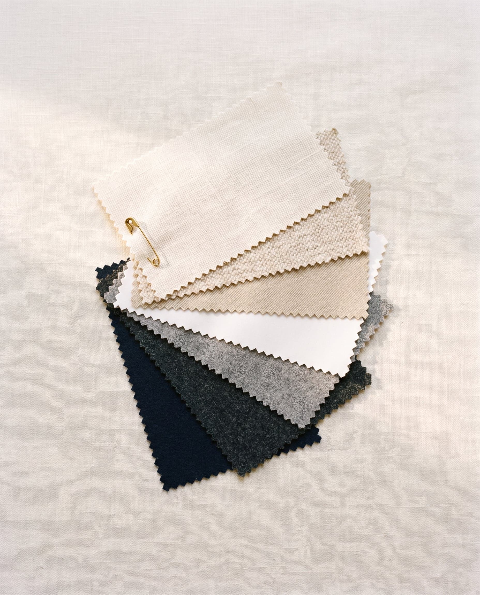Fabric swatches with pinked edges fanned out on linen.