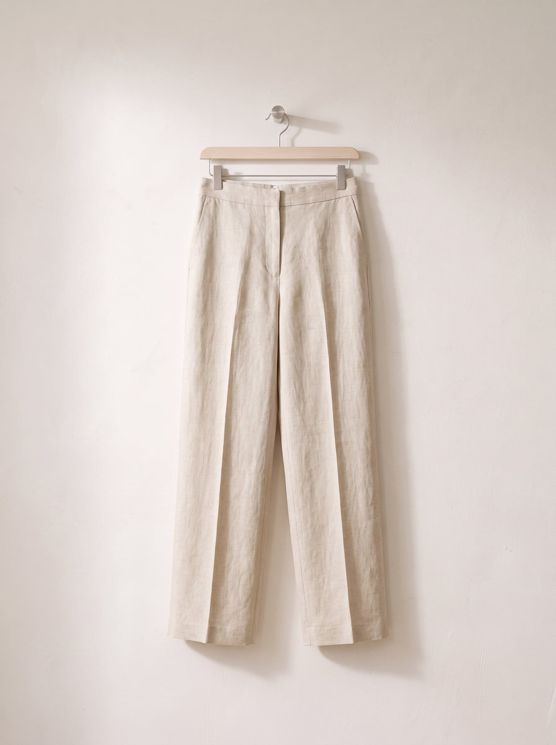 Natural linen wide-leg trousers on a clip hanger.